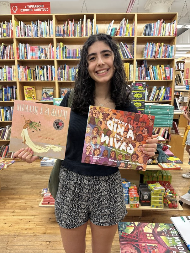 Lori holds up two books in a bookstore.