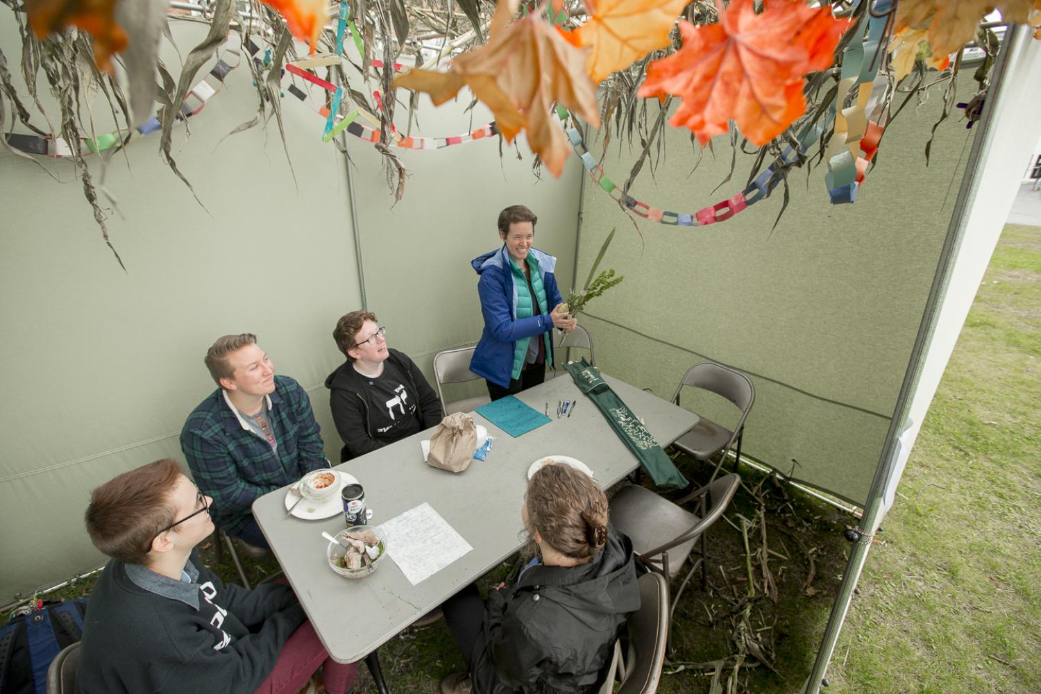 Students sit in the Sukka with Rabbi and observe the Jewish holiday Sukkot